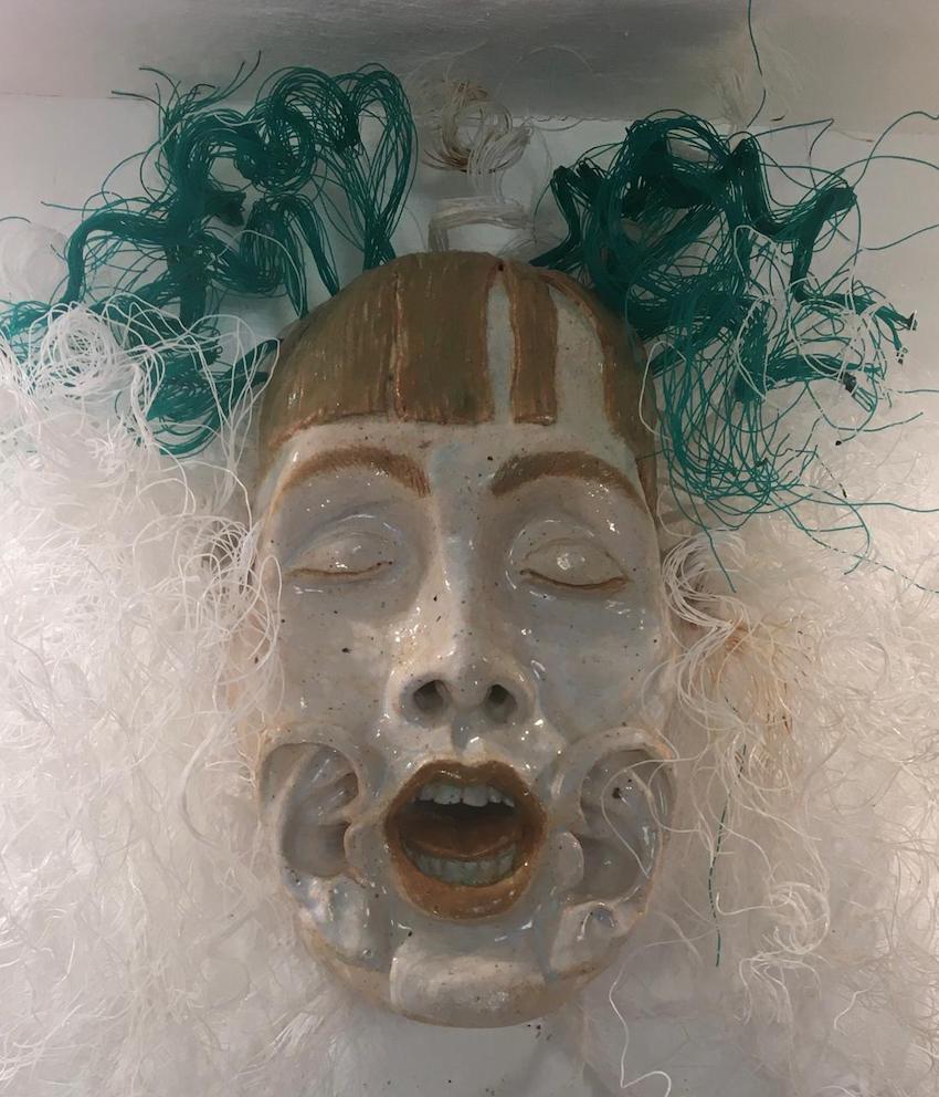 Ceramic mask with green and white fibre hair, by Evan Oberholster
