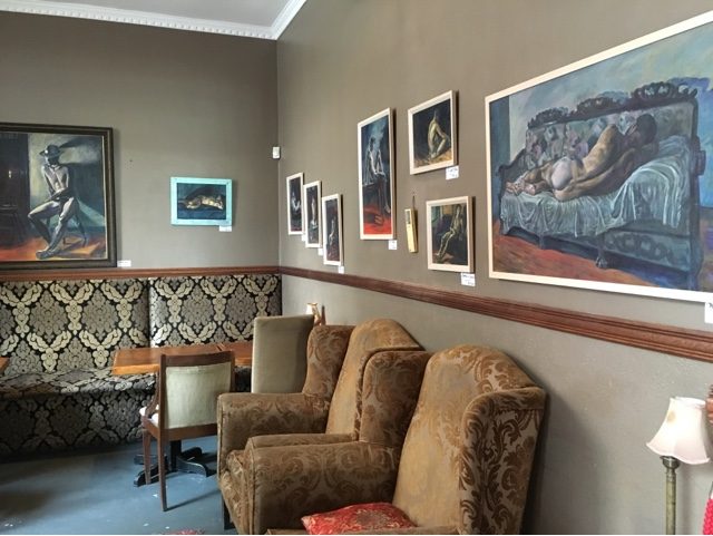 Evan Oberholster’s figurative paintings hung on the walls of a theatre foyer for the exhibition Opening Night