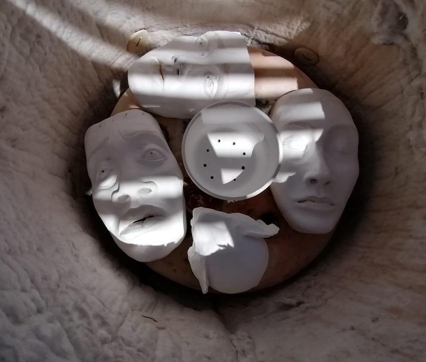 The raku kiln loaded with white ceramic masks before firing