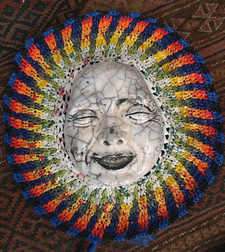 Joyful Craquelé by Evan Oberholster — raku-fired ceramic mask framed by a woven ring of bright rainbow colours