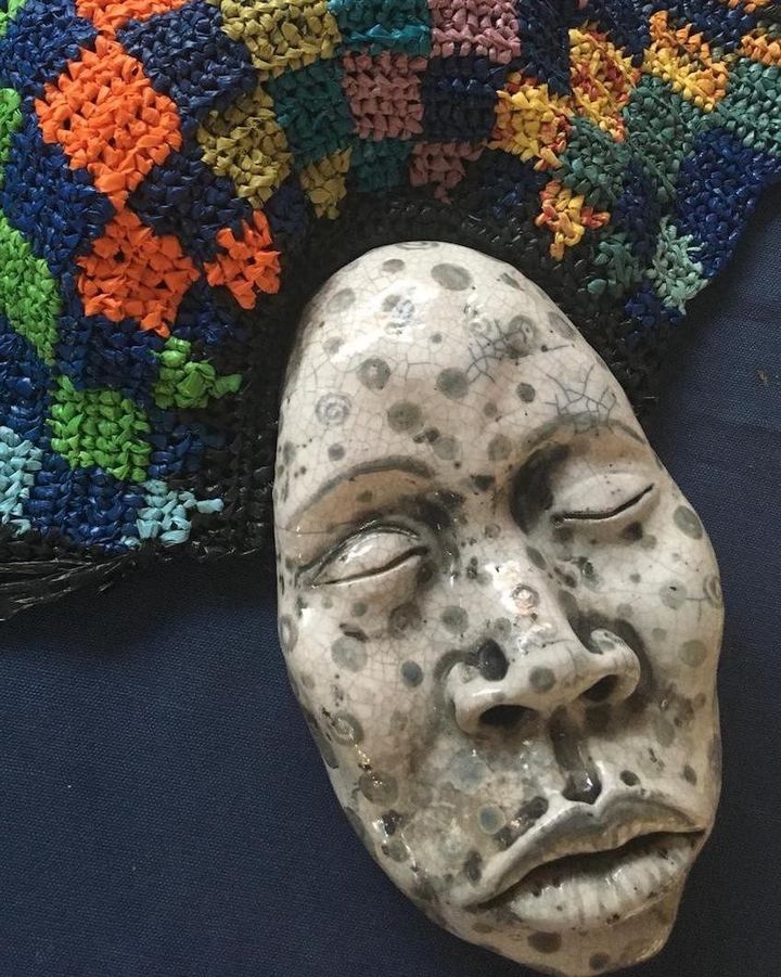 Marks of Fire by Evan Oberholster — spotted ceramic face with a colourful crocheted cap