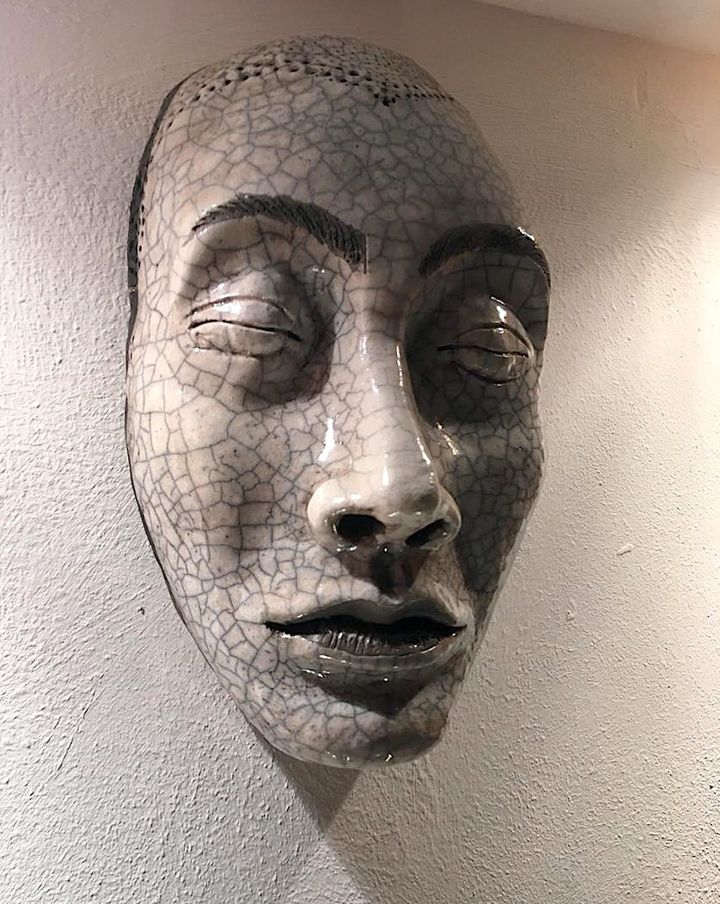 In the Shadows by Evan Oberholster — raku-fired ceramic mask with a crackled white glaze and closed eyes