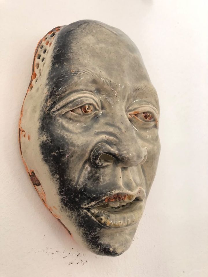 Orange Glow by Evan Oberholster — grey glazed ceramic mask with orange-rimmed eyes and a dark beard