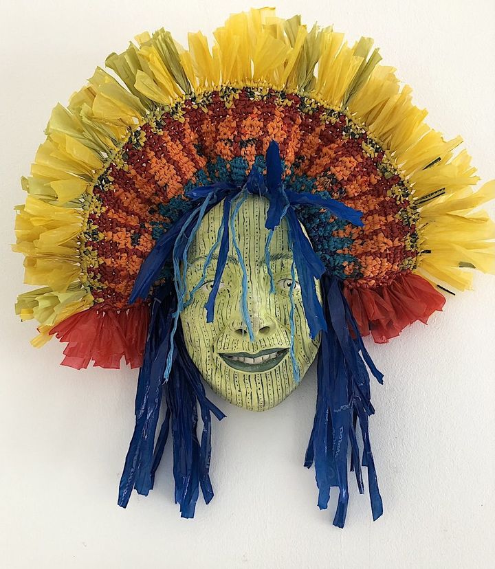 Party Time by Evan Oberholster — green striped ceramic face with blue streamers and a yellow and orange woven crown